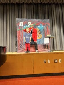 A boy and his father on stage at the school