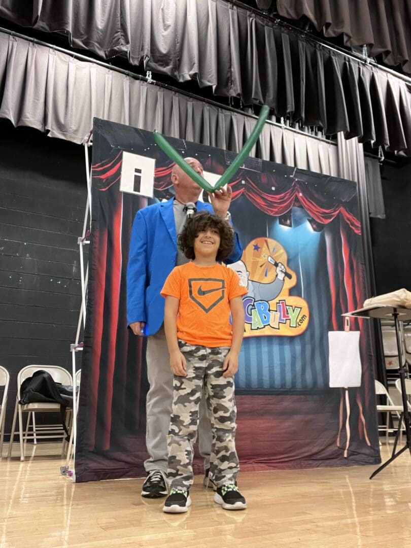 A boy standing next to an adult in front of a backdrop.