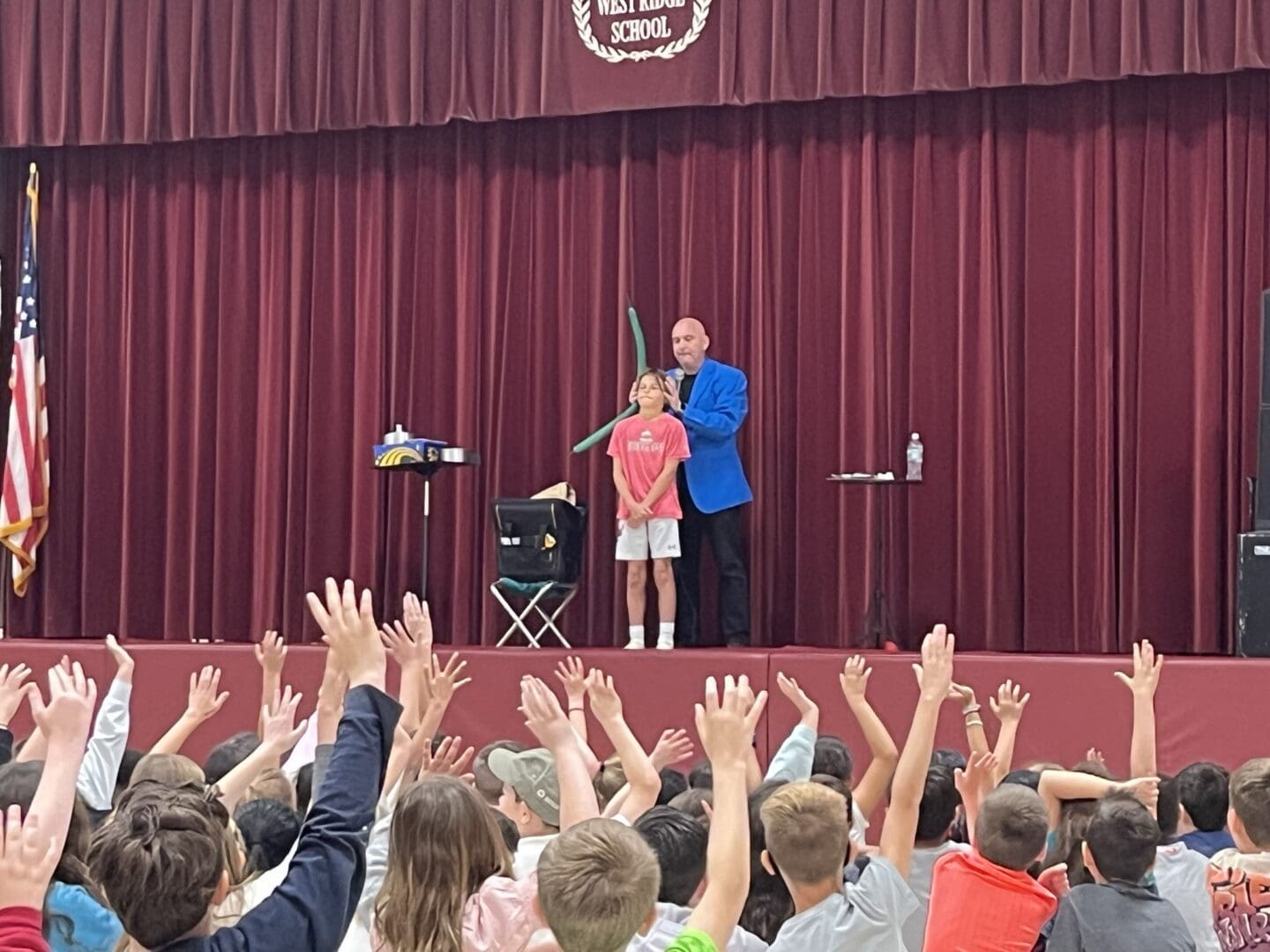 A man and young girl on stage with hands raised.