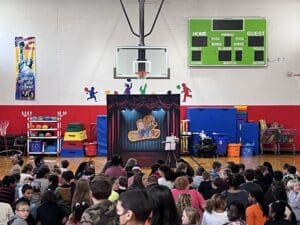 A crowd of people watching an audience in front of a puppet show.