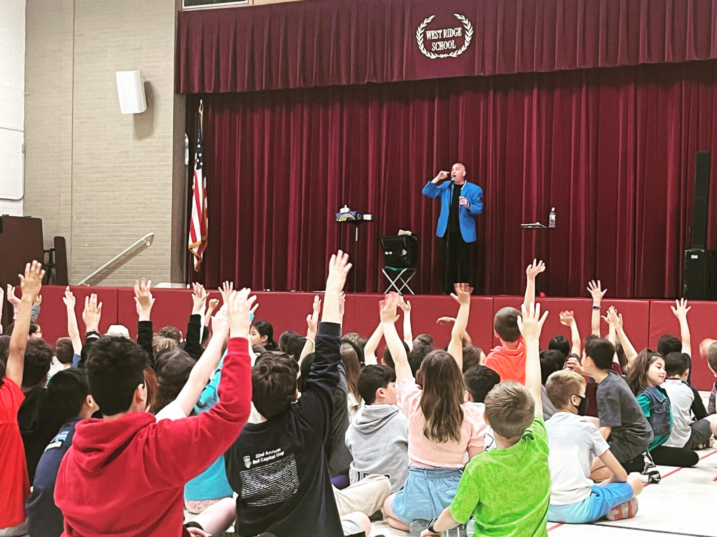 A crowd of people sitting on the stage with their hands raised.