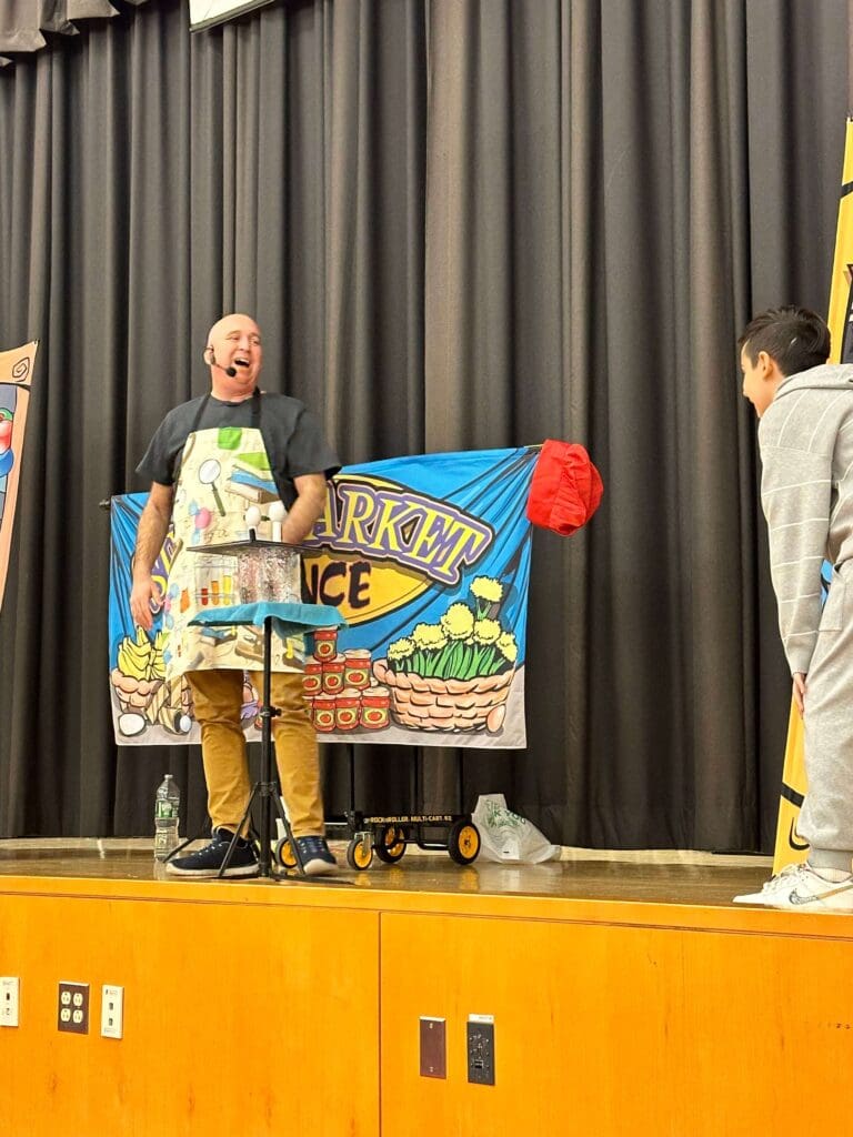 NJ School assembly presenter Michael Kirschner onstage with a volunteer during his STEM school assembly