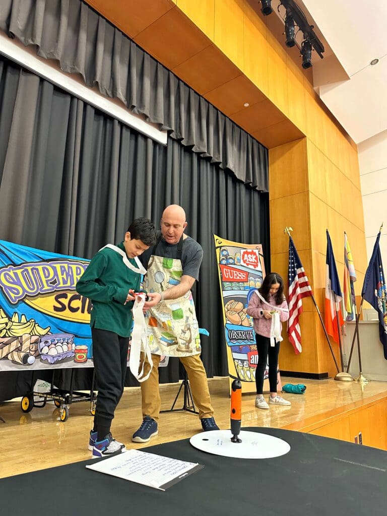 NJ School assembly presenter Michael Kirschner onstage with a volunteer during his STEM school assembly