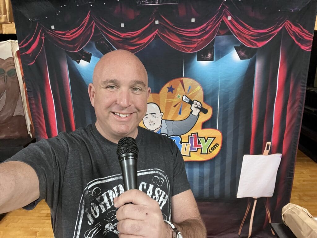 Man holding microphone in front of stage backdrop.